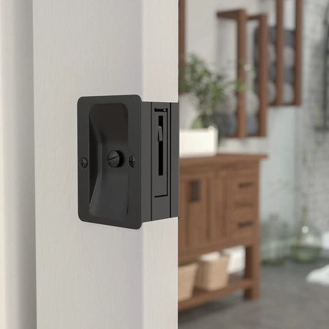 Onward Rectangular Pocket Door Pull with Privacy Lock, Black Finish, Steel, shown on a closed interior door