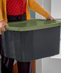 Heavy Duty 17.5 Gallon Plastic Storage Bin With Clear Lid And Full Length Through Wall Handles Gray Opaque Base, being lifted.
