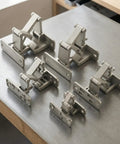 Straight Up Heavy Duty Conceal Hinge For Stone Doors And Fire Cabinets on a gray table, showcasing multiple sizes and angles.