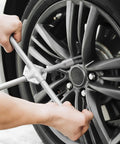 Person using Heavy Hitter 10 Spline Lug Nut Socket Set 3 Piece Deep Well Impact Wrench on a car wheel.