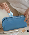 Person placing Double Sided Scrapbooking Tape Runner 4 Pack, 26 Feet By 0.31 Inch into blue pouch beside stationery.