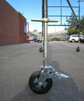 Side view of Set Of Four Eight Inch Caster Wheels With Cast Iron Hubs And Locking Brakes CBM1290 attached to scaffold on outdoor pavement.