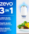Plug In Flying Insect Trap For Fruit Flies And Gnats Using Blue And Uv Light With Zero Mess Adhesive Cartridge To Keep Your Spot Bug Free Includes Two Base Units And Two Sweet Refills That Chase Pests Night And Day For Low Key Indoor Fly Elimination mounted on wall with fruit bowl nearby.