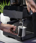 User operating the steam frother on the Next Level Semi Automatic Espresso Machine With Built In Grinder in slick black.