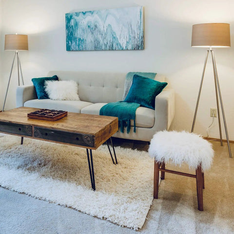 Modern living room with stylish decor, featuring a sofa, wooden coffee table, and ambient lighting from floor lamps. Cozy and contemporary.
