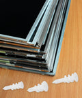 Heavy Duty Drywall Anchors Kit, 300-Piece Plastic Anchors with Spiral Expansion Tubes next to stacked metal frames on a table.