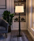Benjamin Traditional Floor Lamp Satin Black Finish With Resin Construction next to a grey armchair in a cozy living room scene.
