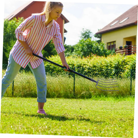 Person using Multi Functional Manure Fork For Lawn Care And Farm Use A Rugged Heavy Duty Pitch Fork For Clearing Debris And Manure.