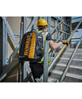 Man carrying a Massive 40 Liter Tool Backpack Built Tough As Nails For Contractors up construction stairs.