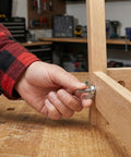 Hand fastening a 5/16-18 zinc plated wing nut on wooden furniture with carbon steel butterfly hardware.