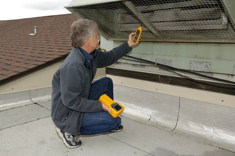 Technician using Top Dollar Digital Dual Panel Temperature Humidity Meter With No Sweat Dew Point Tracking on rooftop.