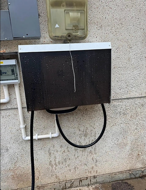 Super Tough Outdoor Electric Charger Rain Cover Hella Rugged Weatherproof Box mounted on a wall with rain droplets.