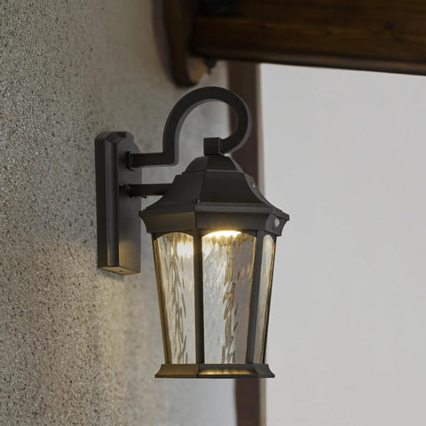 Heavy Duty Led Motion Sensor Outdoor Wall Light With 800 Lumens Super Bright 3000K Warm White Glow, Dusk To Dawn Safety Switch, Rugged Black Metal And Clear Water Glass Finish mounted on a textured wall.