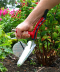 Multi Digger Dual Grip Garden Hand Trowel with Soft Touch Ergonomic Handles used in flower bed weeding task.