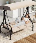 Woman relaxing on 3-Seater Outdoor Porch Swing with Adjustable Backrest and Canopy in daybed mode, beige cushions for comfort.