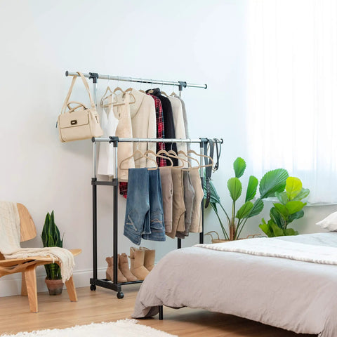 Heavy Duty Double Rod Clothes Rack With Smooth Rolling Lockable Wheels And Height Adjustable Extendable Bar holding clothes and a bag.