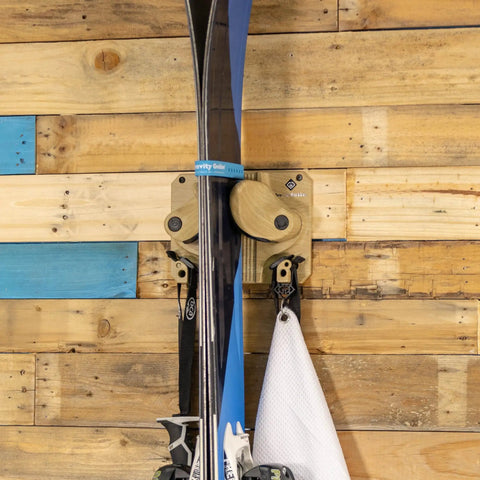 Ski And Snowboard Wall Mount Rack For Garage And Home Storage with solid wood hooks holding skis securely on a wall.
