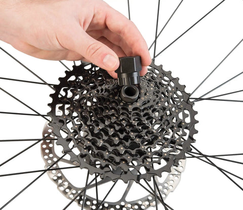 Hand using FR-5.2 Bicycle Cassette Lockring Tool With 12-Spline Design on Shimano disc brake lock rings in bike wheel maintenance.