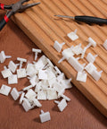 100 Pack Nylon PCB Adhesive Standoffs For Circuit Boards 0.25 Inch Insulated Spacers scattered on a wooden surface with tools.