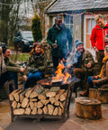 34 Inch Outdoor Indoor Firewood Rack With Bronze Finish holding logs near fireplace at outdoor gathering, enhancing drying airflow.