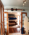 Top Shelf Heavy Duty Bamboo Ski Wall Mount Rack For Garage Storage holding skis above doorway in a stylish indoor space.