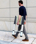 Person carrying Twelve Point Five Foot Telescoping Ladder For Home RV And Attic Use Collapsible Aluminum Alloy Extension Ladder outdoors