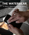 KUVRD Waterbear white screen-cleaning patch used on a black smartphone; front view of hands cleaning the device