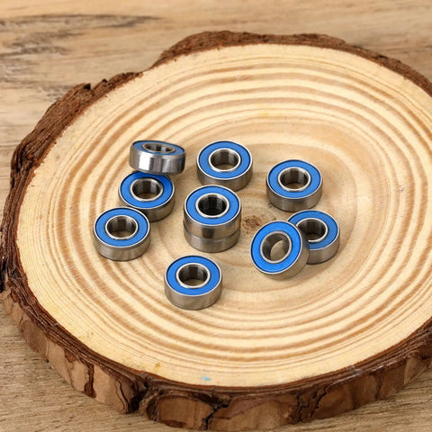 10-Pack MR115-2RS Miniature Deep Groove Ball Bearings Featuring Double Rubber Seals And Chrome Steel Construction With 5mm Inner Diameter 11mm Outer Diameter And 4mm Width on wooden surface.