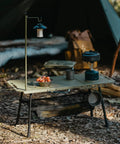 Grab And Go Tactical Camping Table With Adjustable Height, collapsible lightweight folding table set up in a forest environment.