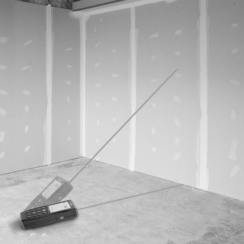 Micro Laser Distance Meter With Bluetooth Sync And Tilt Sensor measuring in a room with unfinished drywall walls.