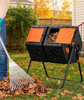 Person raking leaves next to Double Chamber Rotating Compost Tumbler 170L Outdoor Bin With Elevated Base, Hands Free, in garden setting.