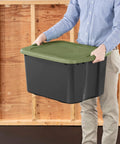 Person holding Heavy Duty 17.5 Gallon Plastic Storage Bin With Clear Lid And Full Length Through Wall Handles Gray Opaque Base.
