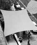 14 By 14 Ft Gray Waterproof Shade Sail Square For Backyard Chill Keeps You Cool And Shaded Blocks 95 Percent UV Rays And Rain Runoff Heavy Duty 220GSM PU Coated Fabric installed over a street during rain with a close-up of water droplets on fabric.