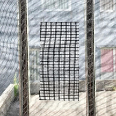 Heavy Duty Window Screen Repair Tape And Mesh Patch Kit 2 Inches By 16 Feet Long Black adhesive mesh patch on window.