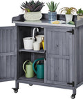 Mobile Outdoor Potting Bench Table With Castors On Wheels Solid Wood Workstation And Large Storage Cabinet Durable Metal Top Garden Station For Potting DIY Projects Flower Arranging And More Gray showcasing open cabinet with gardening tools and potted plants