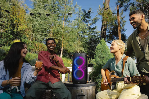 Outdoor party with four people and PartyBox 110 Portable Party Speaker With Built In Lights And Deep Bass 160W Power.