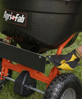 Person attaching Three Direction Spreader Deflector Kit For 110Lb Push And Tow Spreader, Easy Tool Free Attachment, on grass