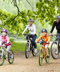 Family cycling on a forest trail, two adults and two children on mountain bikes, wearing helmets