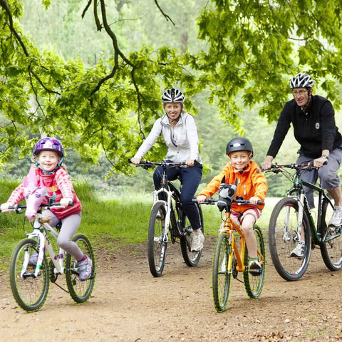 Family cycling on a forest trail, two adults and two children on mountain bikes, wearing helmets
