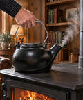 Solid Cast Iron Wood Stove Steamer And 3 Qt Humidifier Kettle showcasing steam rising, featuring chrome handle on a wood stove.