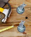 Four Pack Threaded Stem Swivel Caster Wheels With Rock Solid Lockable Brakes For Super Smooth Gliding Action on a wooden surface with tools.