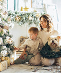 Woman and child decorate Christmas tree with Indoor 2 Pack G50 LED String Lights With Vintage Filament Bulbs, dog with wreath nearby.