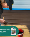 Person applying Dark Cocoa stain on wooden deck using Solid Color Wood Stain For Decks And Fences UV Resistant Opaque Finish