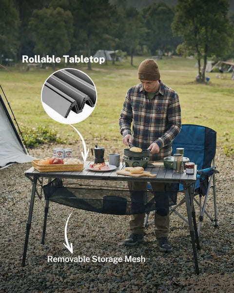 Man using 50 Inch Camping Table With Adjustable Height Legs For Uneven Ground, Easy Setup Portable Folding Aluminum Roll-Up Table With Mesh Pocket for outdoor cooking.
