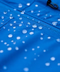Water beading on blue fabric treated with Revivex DWR Spray For Waterproof Jackets And Rain Gear Keeps Your Gear Dry And Gore-Tex Breathable