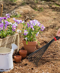 Nine Tines Metal Garden Hand Rake Set For Yard Lawn And Flower Beds Mini Cultivator Tools With Easy Grip Handle used for soil loosening near flowers.