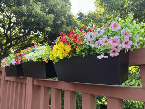 Set Of Four Heavy Duty Metal Railing Planters, 16 Inch Rectangular Window Boxes with vibrant flowers on a railing.