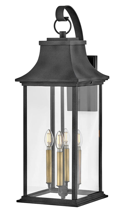 Extra Large Outdoor Wall Lantern Featuring Heritage Brass And Aged Zinc Finish, showcasing three candle lights behind clear glass.