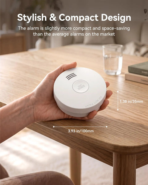 Straight Up No Fuss Smoke Detector And Fire Alarm With A 10 Year Sealed Battery and Photoelectric Sensor for Lightning Fast Smoldering Fire Alerts UL217 Certified, compact design in hand on a table.