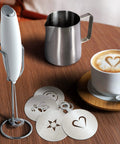 Complete Home Coffee Frother Set With Upgraded Ultra Stand Barista Grade Handheld Milk Foam Maker Mini Blender Whisk Frothing Pitcher Stencils And More Perfect Gift For Lattes Cappuccinos Mochas And Matcha At Home on wooden table with stainless pitcher, foam art stencils.